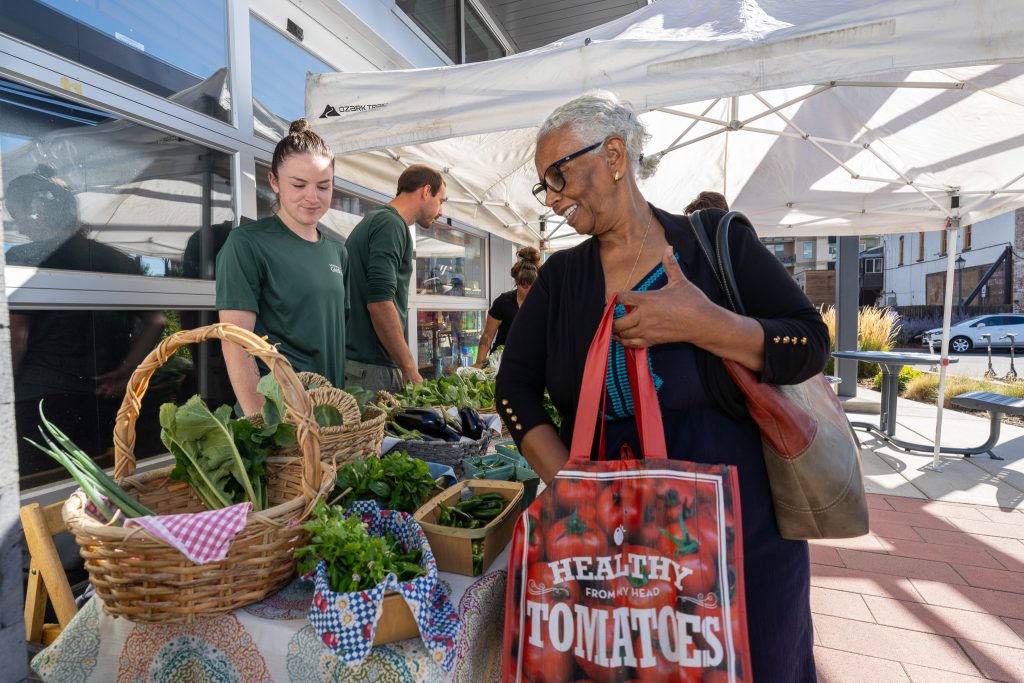 Woman shops for fresh produce from the Botanic Gardens hosted at the Denver Housing Authority Central Office